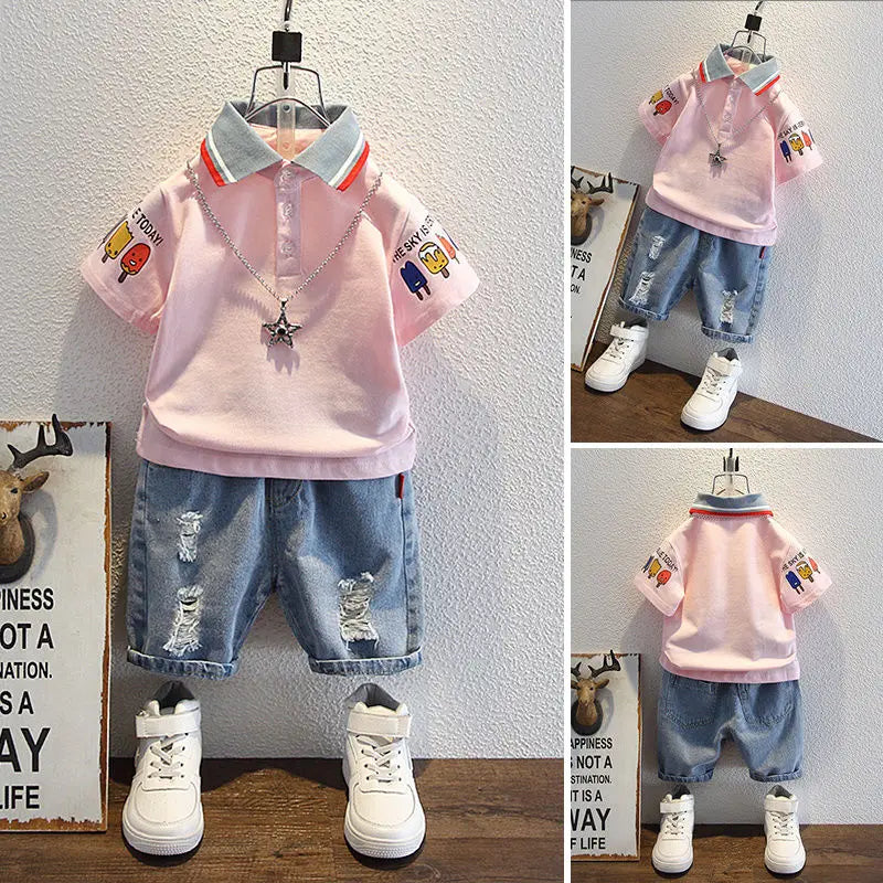 Children's outfit with pink shirt, blue jeans, and white sneakers on a wooden floor.