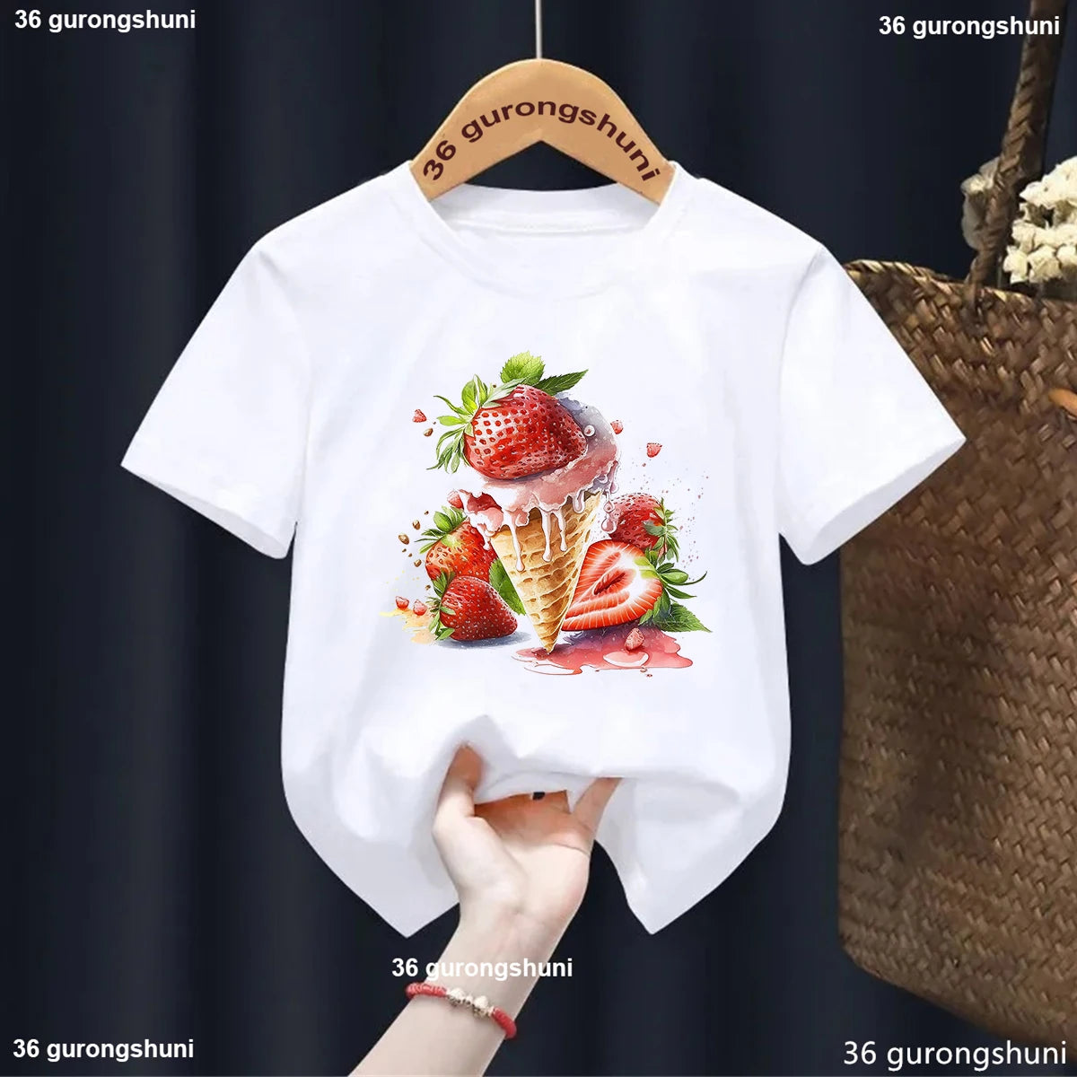 White t-shirt with strawberry ice cream design on a hanger against a dark background.