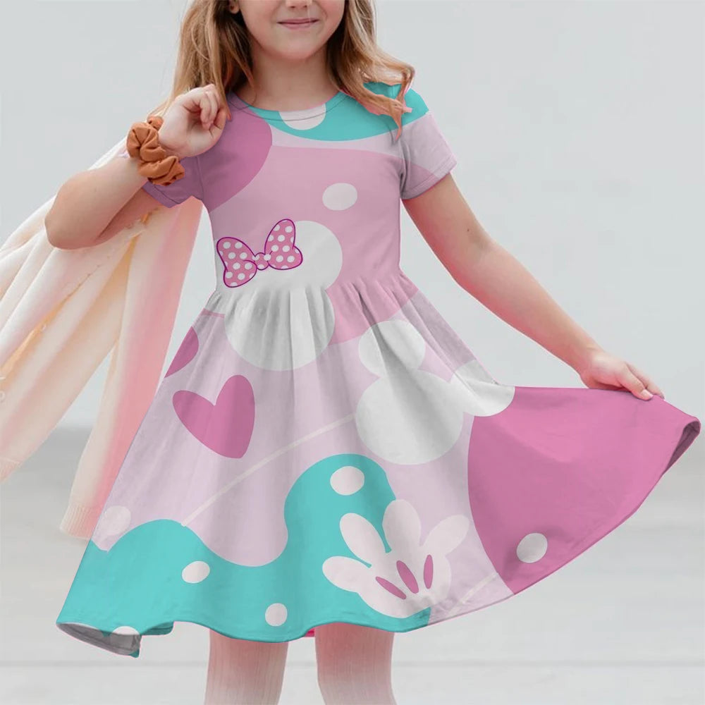 Child wearing a pink dress with a bow and heart designs on a plain background