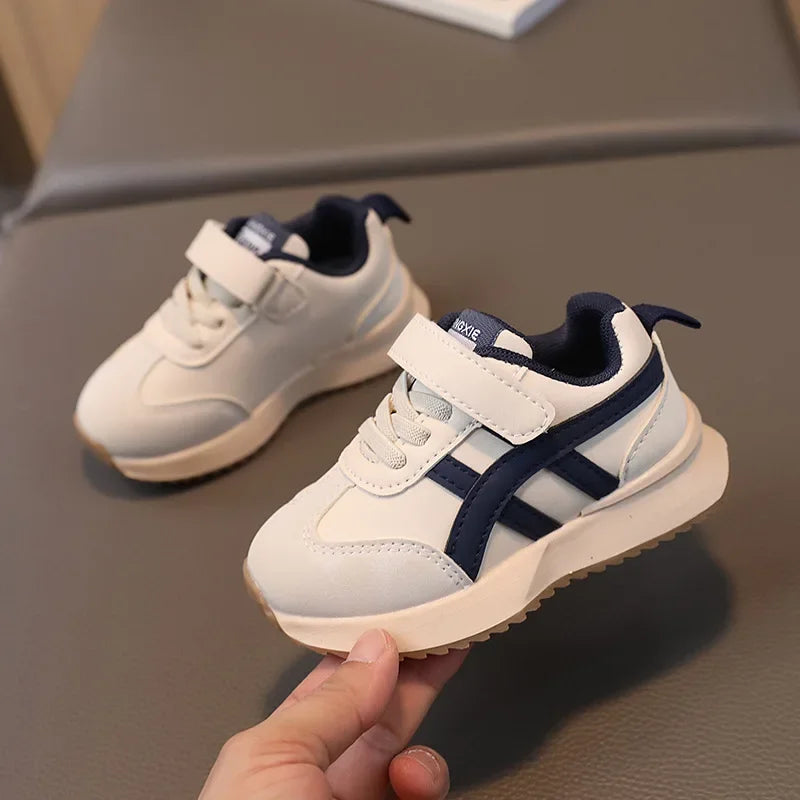 White and navy children's sneakers on a gray surface
