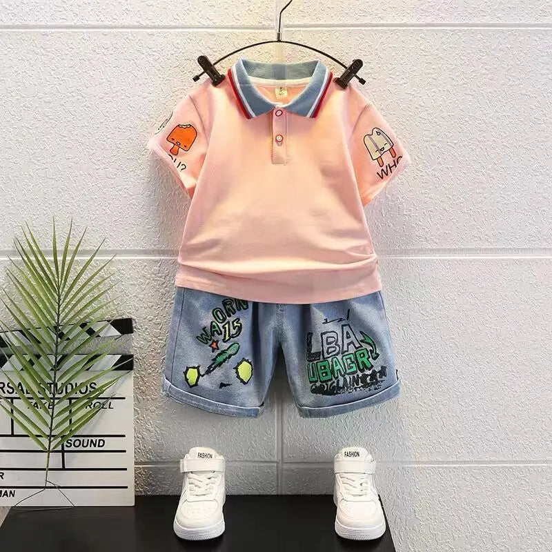 Children's outfit with pink polo shirt and denim shorts on a hanger against a white wall.