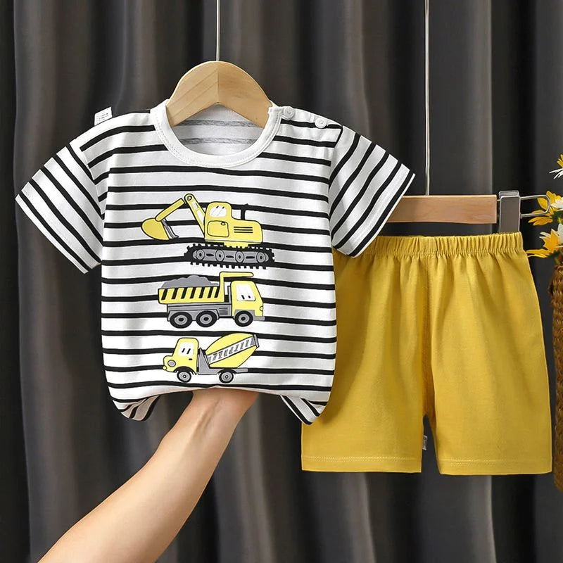 Children's striped t-shirt with construction vehicle design and yellow shorts on a hanger against a dark curtain background.