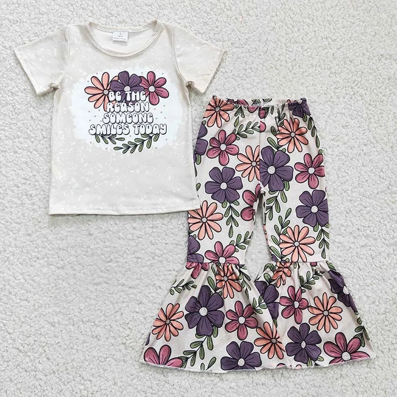 Children's t-shirt and floral pants set on a textured surface