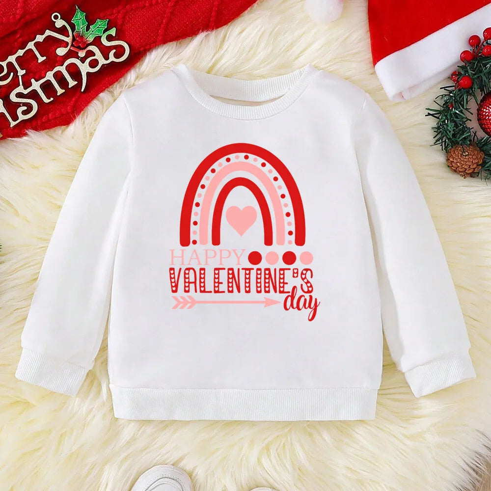 White sweatshirt with Valentine's Day design on a textured surface with Christmas decorations.
