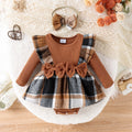 Baby outfit with plaid dress and brown long-sleeve top on a textured surface