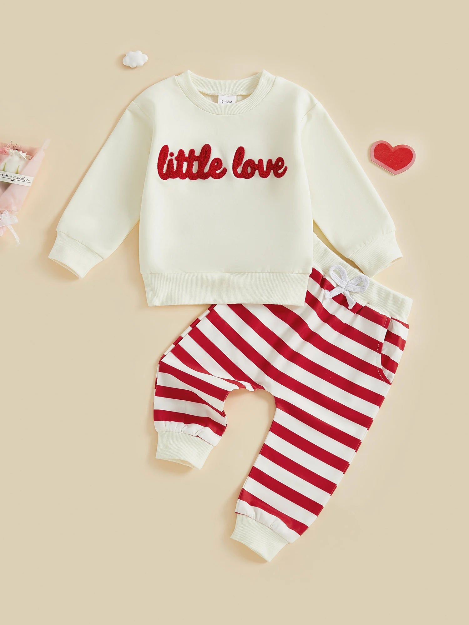Children's outfit with white sweatshirt and red striped pants on a beige background