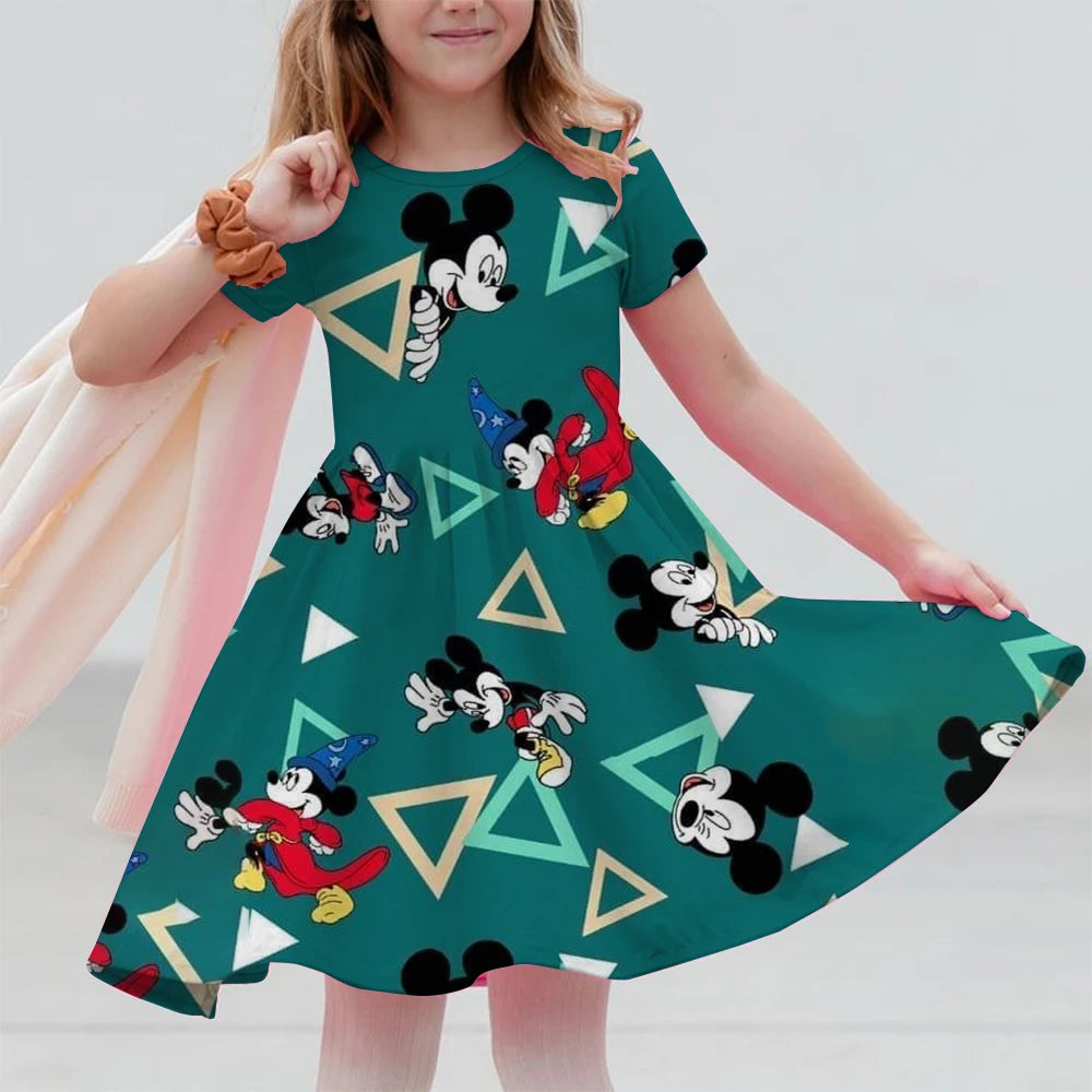 Child wearing a green dress with Mickey Mouse patterns on a plain background