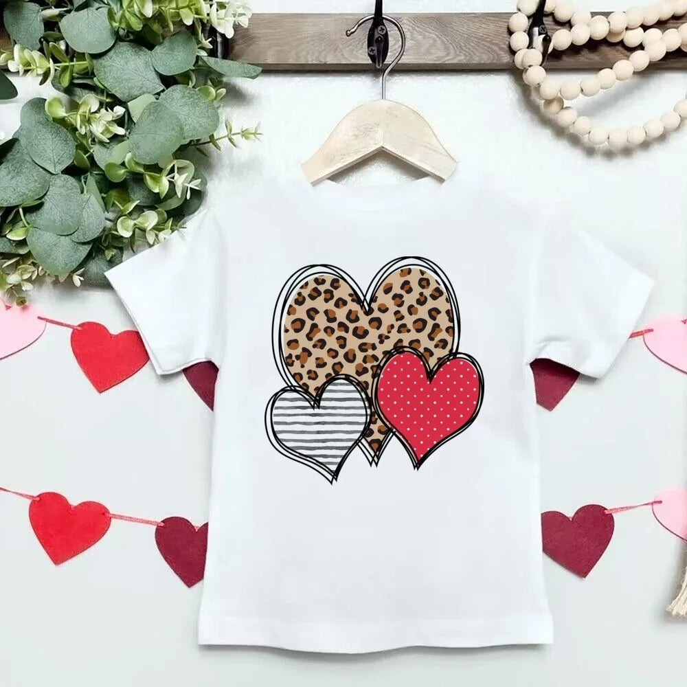 White t-shirt with heart designs on a hanger, surrounded by decorative elements.