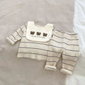 Baby outfit with striped shirt, bib, and pants on a neutral background