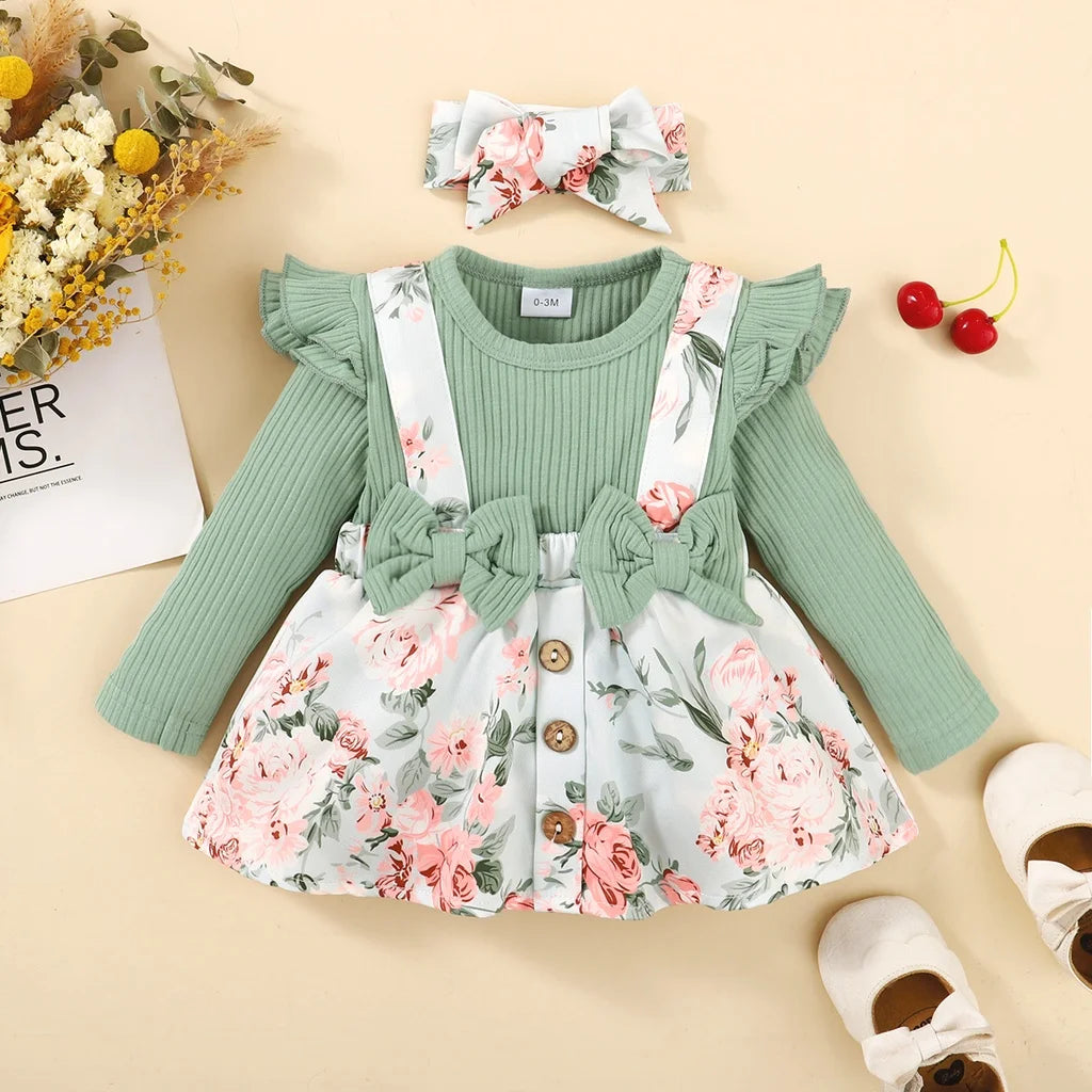 Children's outfit with green top, floral dress, and headband on a beige background