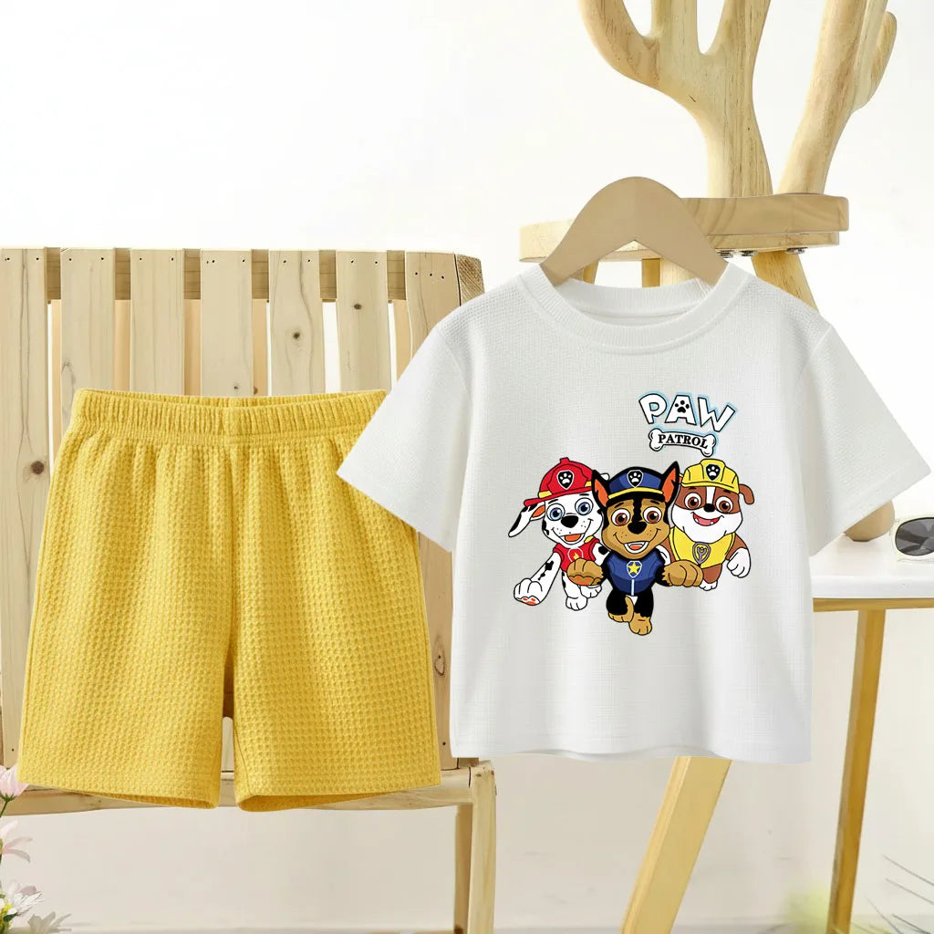 White t-shirt with Paw Patrol design and yellow shorts on a wooden chair.