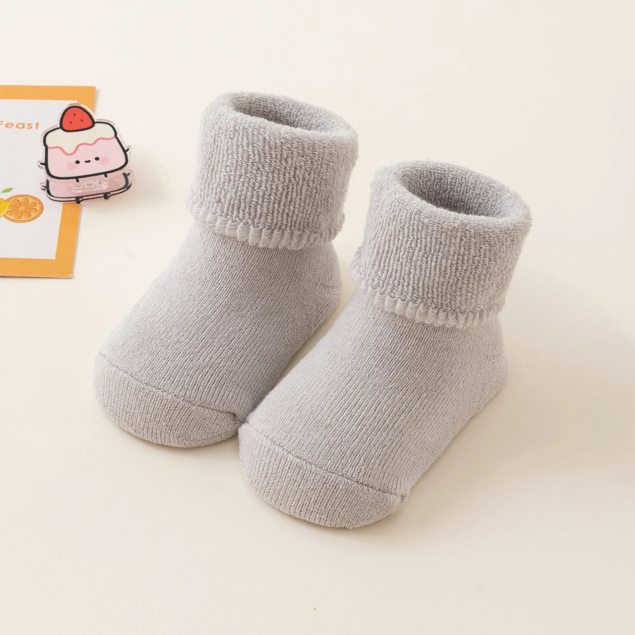 Pair of gray baby socks on a light beige background
