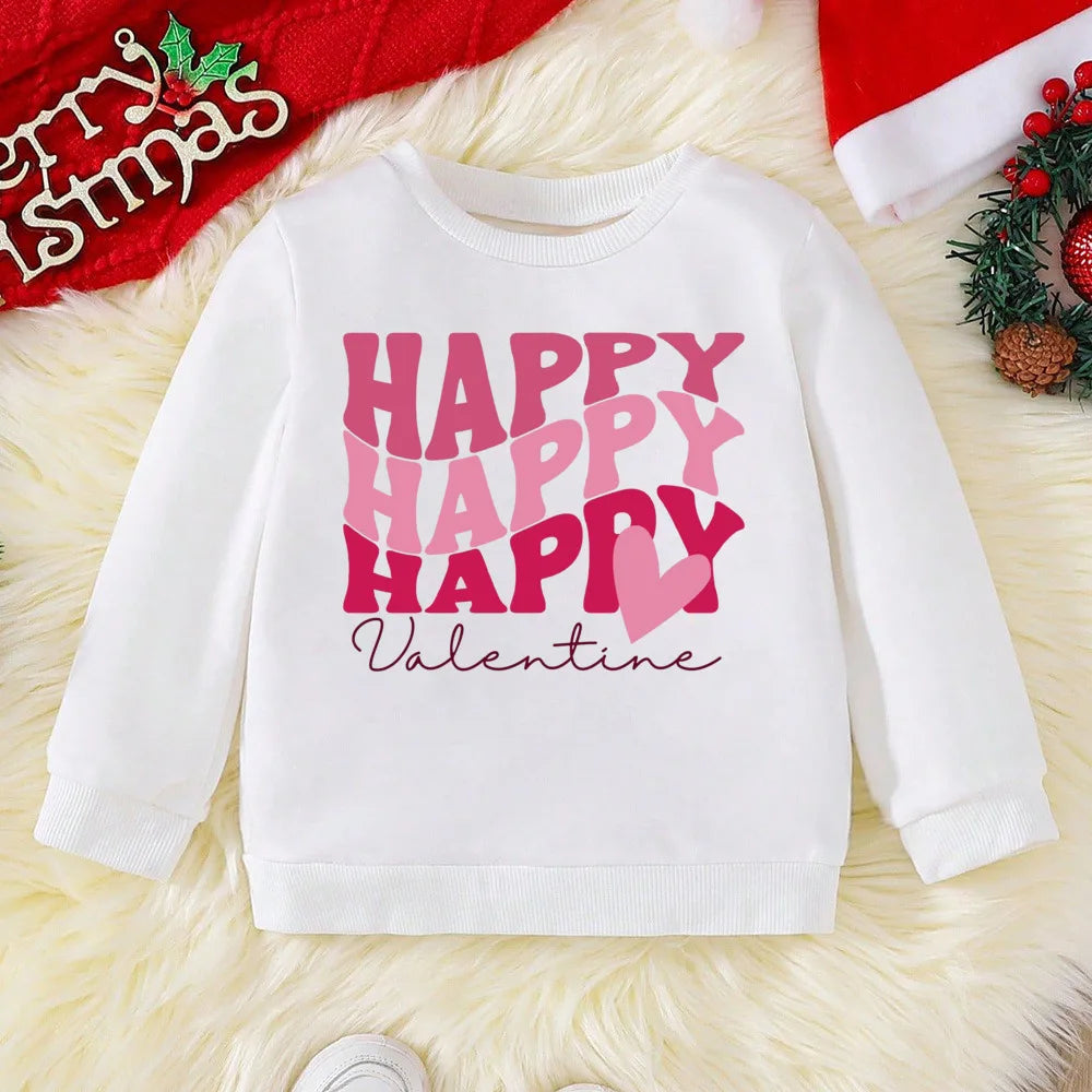 White sweatshirt with 'Happy Happy Happy Valentine' text on a textured surface with Christmas decorations.