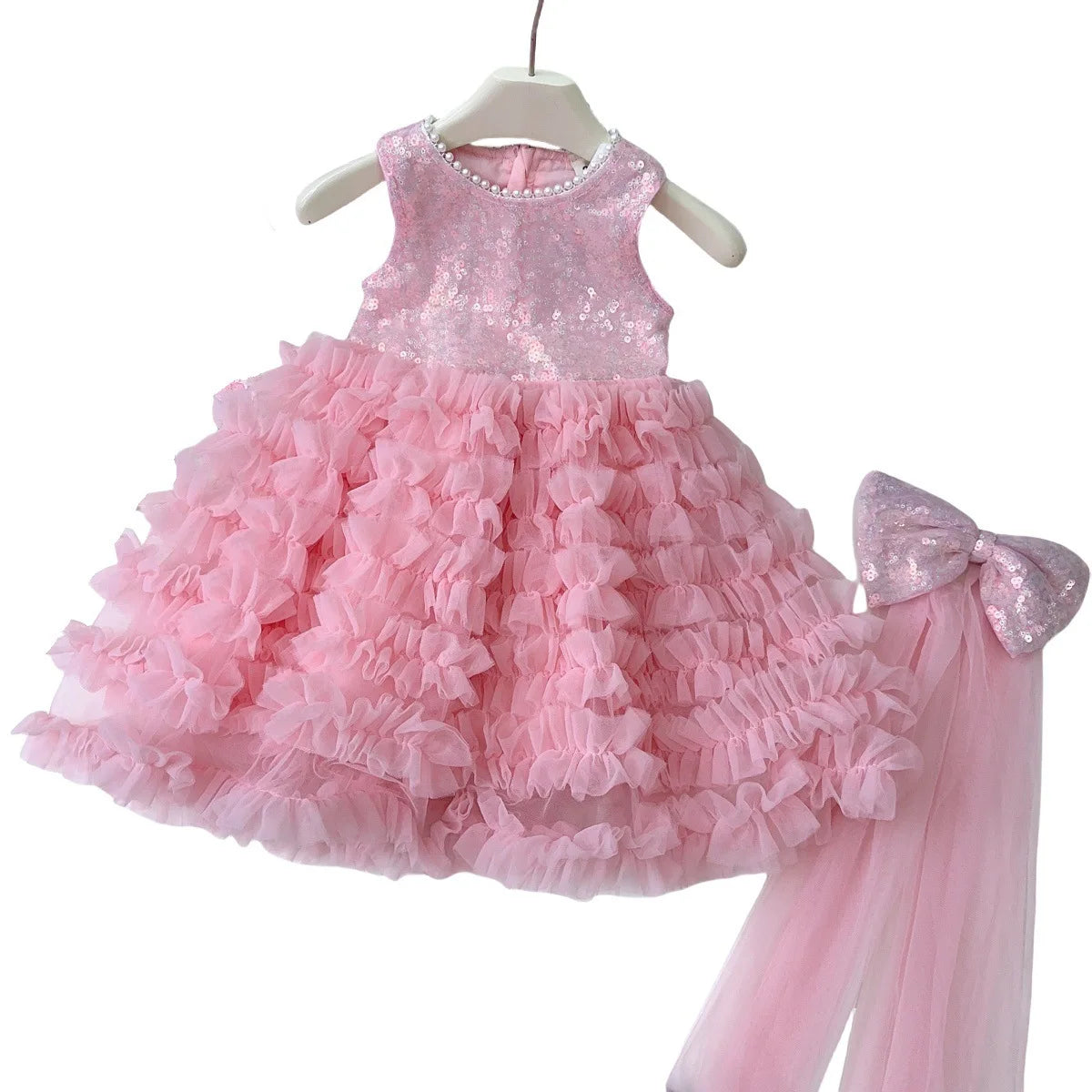 Pink dress with ruffled skirt and matching bow on a white background