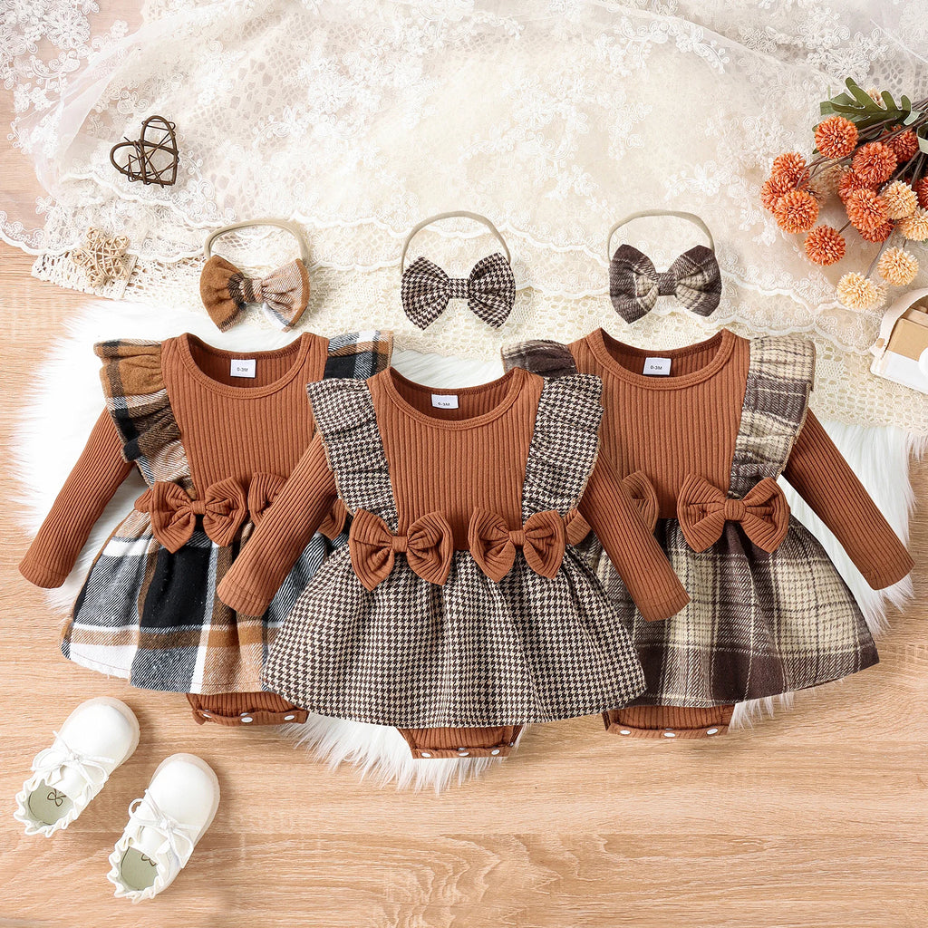 Three baby outfits with plaid skirts and brown tops on a wooden surface, accompanied by hair bows and shoes.