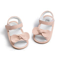 Pair of pink baby sandals with bows on a white background