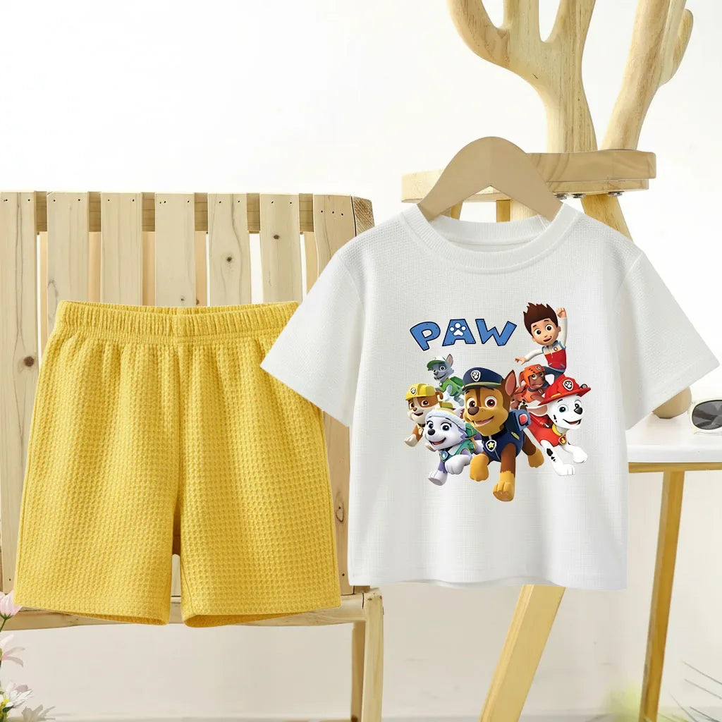 White t-shirt with Paw Patrol design and yellow shorts on a wooden chair.
