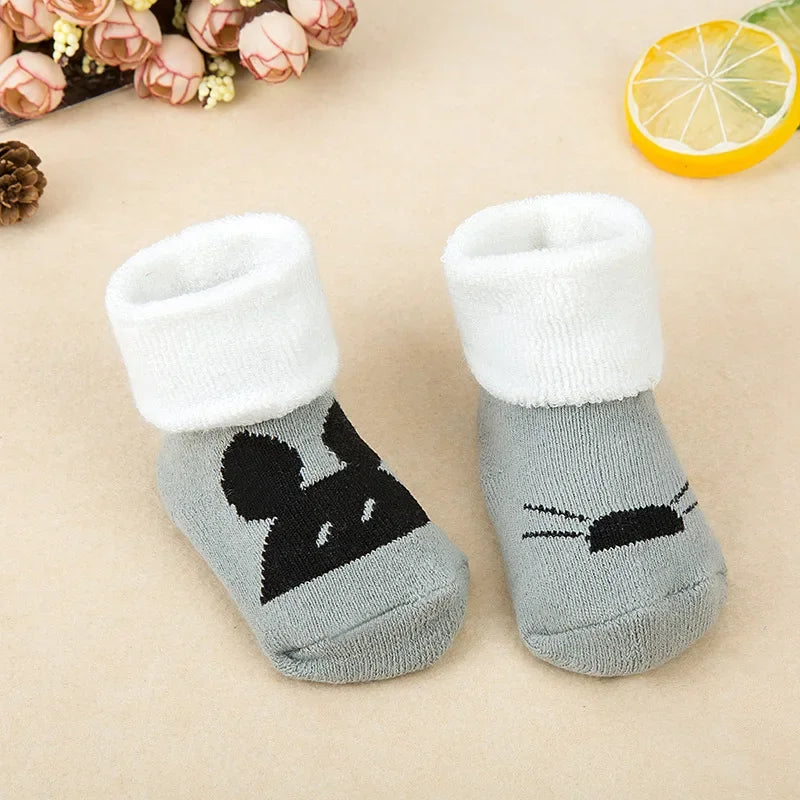 Gray baby socks with black mouse design on a beige background