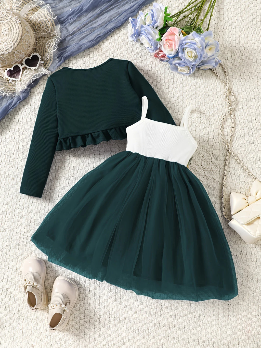 Green dress with white top on a textured surface with flowers and shoes.