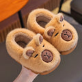 Pair of plush animal slippers with bear faces on a gray surface.