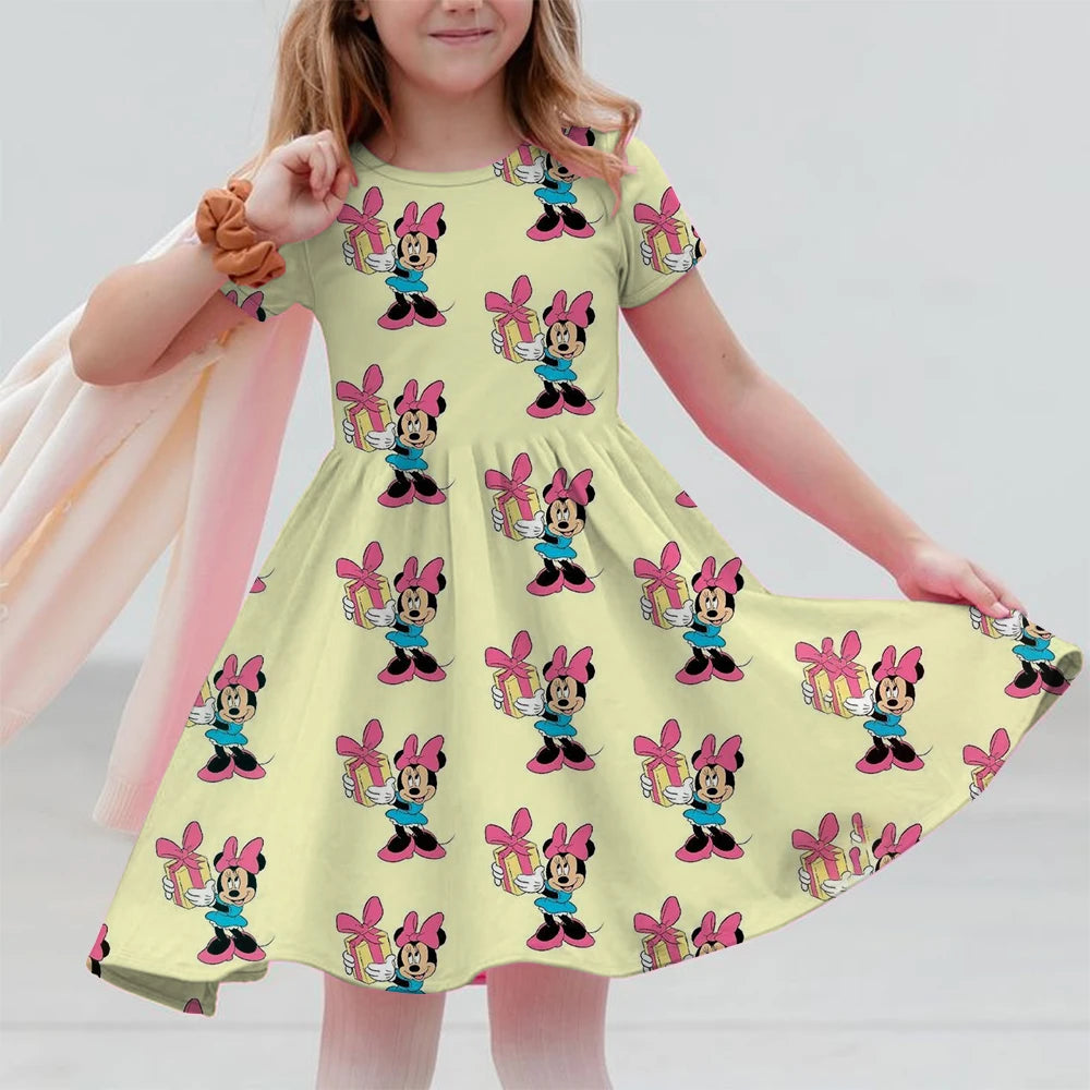 Child wearing a yellow dress with cartoon character pattern on a plain background