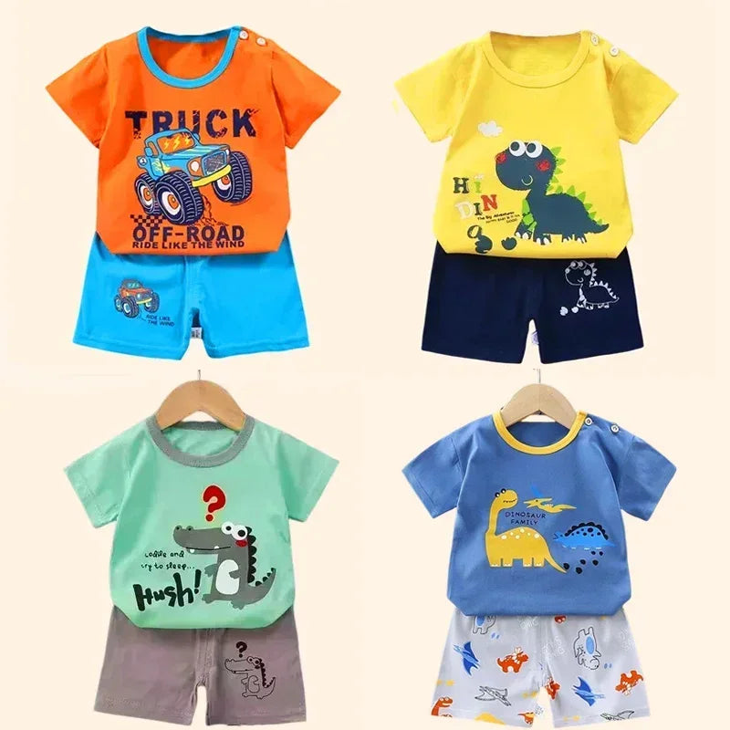 Four children's outfits with colorful t-shirts and shorts on hangers against a beige background.