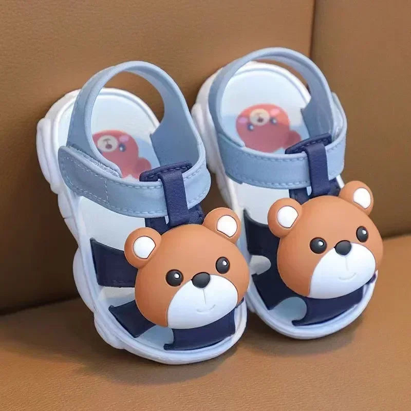 Pair of children's sandals with bear character design on a brown surface
