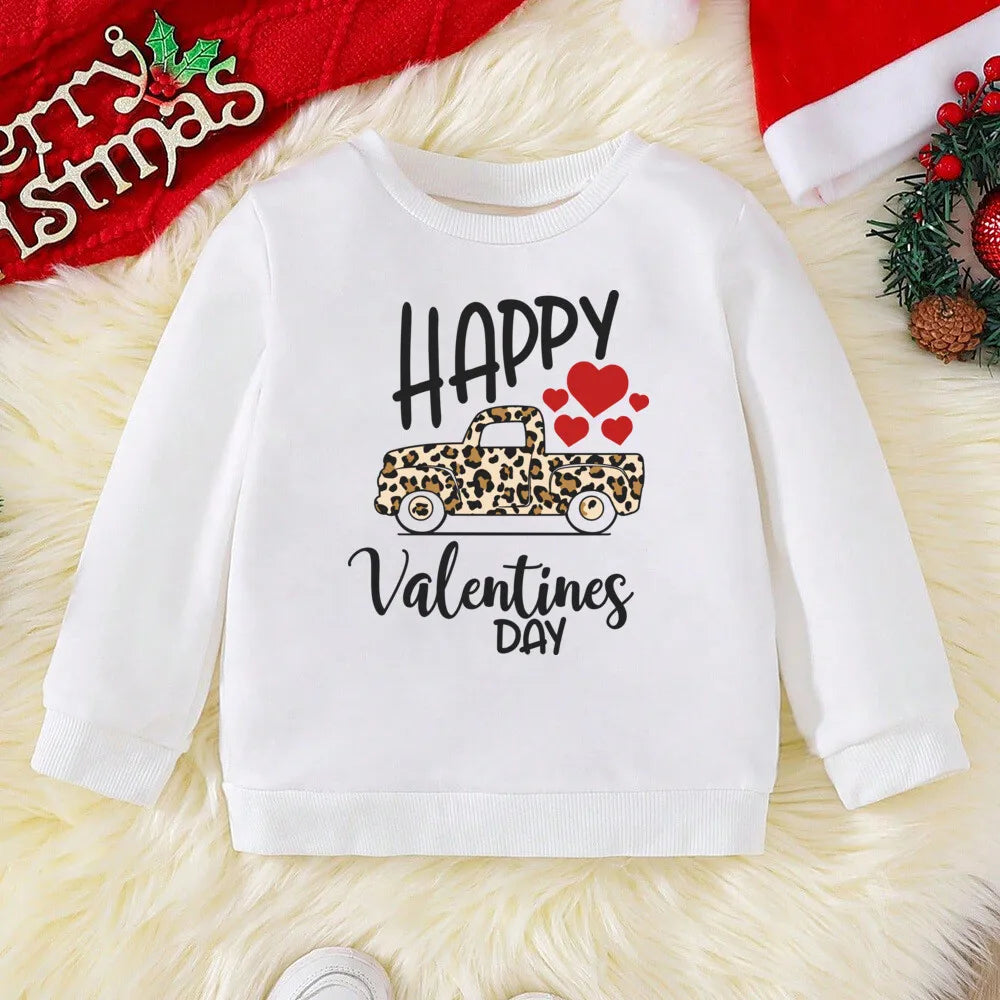 White sweatshirt with Valentine's Day design on a textured surface with Christmas decorations.