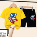 Yellow t-shirt and black shorts with Captain America design on hangers against a white background.