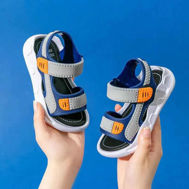 Children's sandals with blue, gray, and orange design held against a blue background