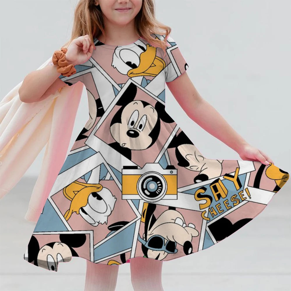 Child wearing a dress with cartoon character prints on a plain background