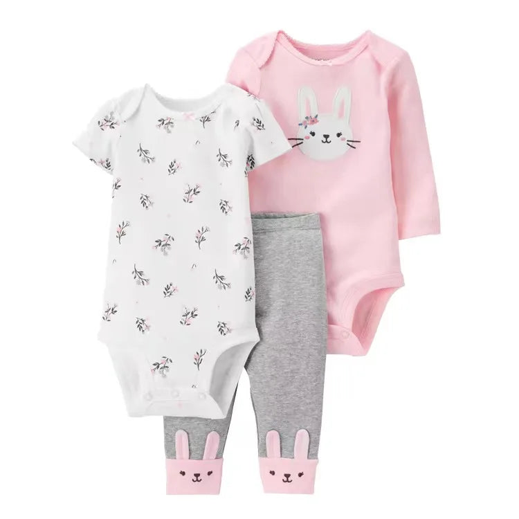 Set of baby clothing including a pink onesie, white floral onesie, and gray pants with bunny ears on a white background.
