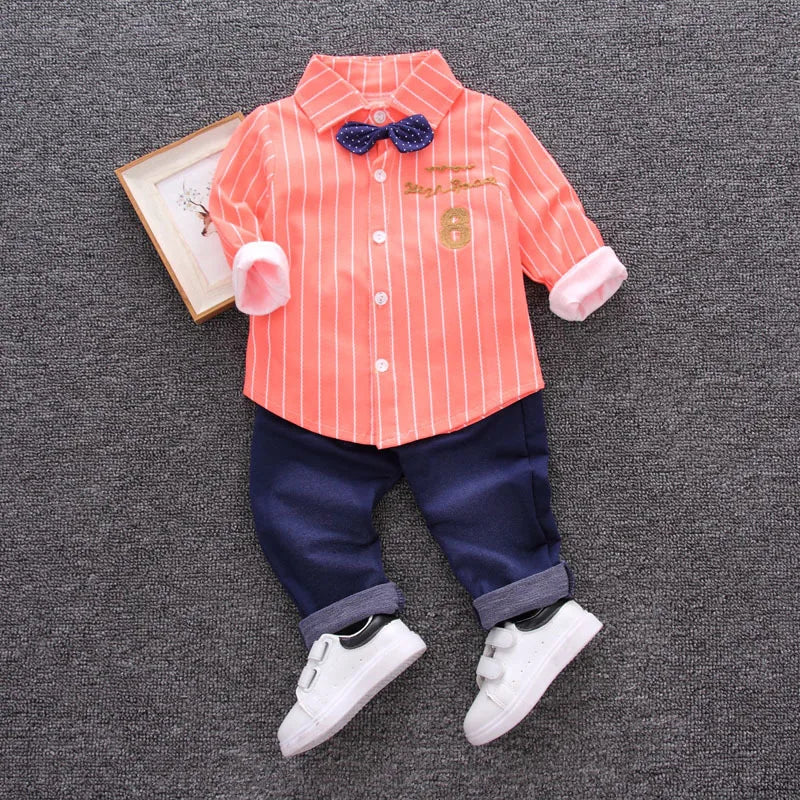 Children's outfit with striped shirt, pants, and shoes on a textured gray background