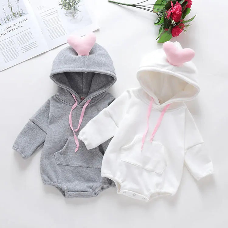 Two baby hoodies, one gray and one white, with pink accents on a light surface.
