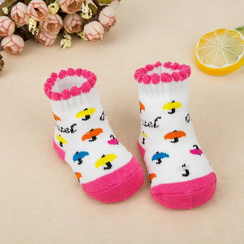 Pair of children's socks with colorful patterns and pink accents on a beige background.