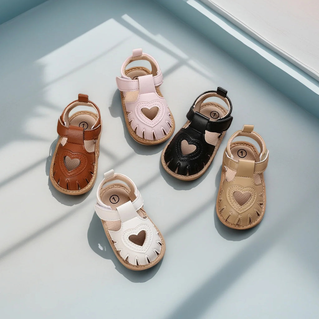 Set of five children's sandals with heart designs on a light surface