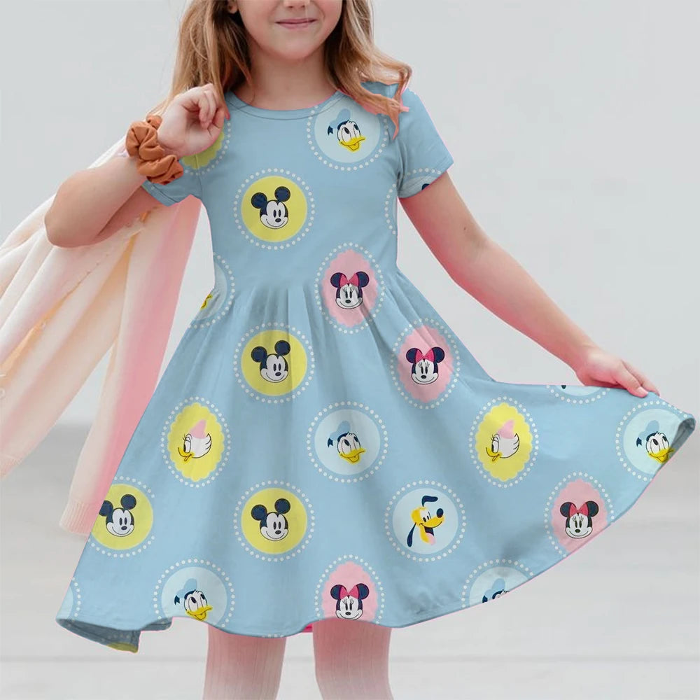Child wearing a light blue dress with cartoon character patterns on a plain background