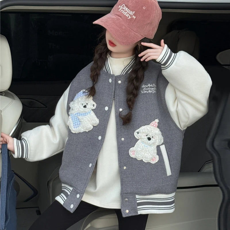 Person wearing a gray varsity jacket with dog patches in a car.