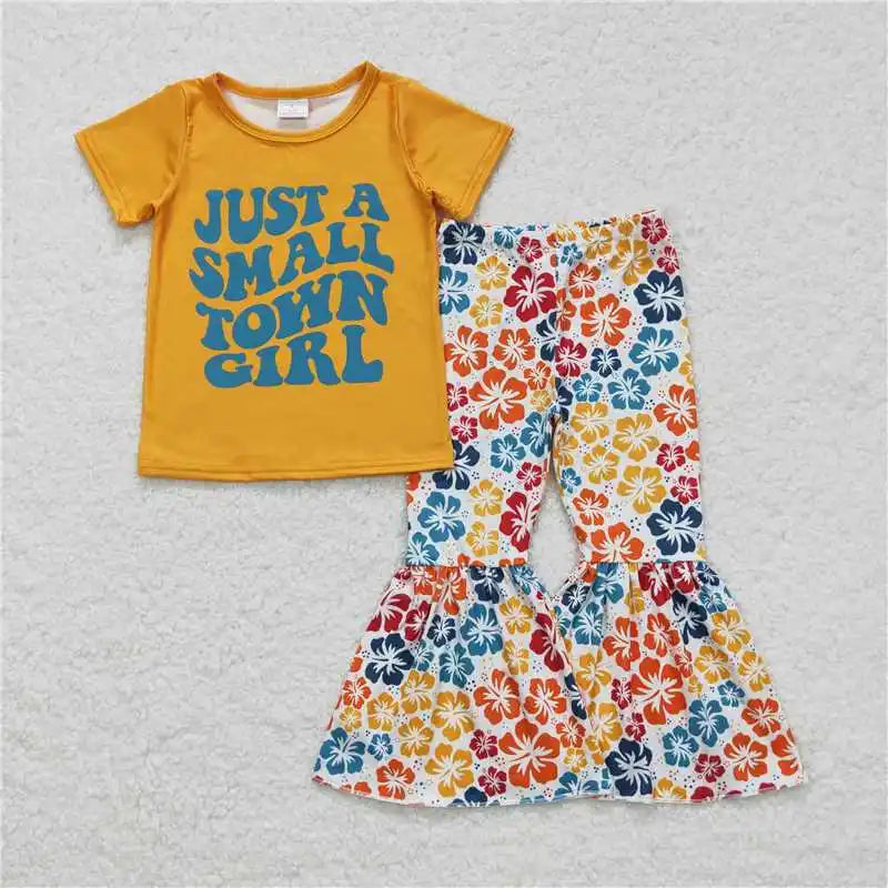 Yellow t-shirt with 'Just a Small Town Girl' text and floral pants on a gray background