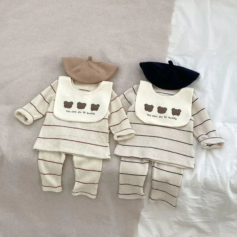 Two baby outfits with striped shirts, bibs, and hats on a neutral background