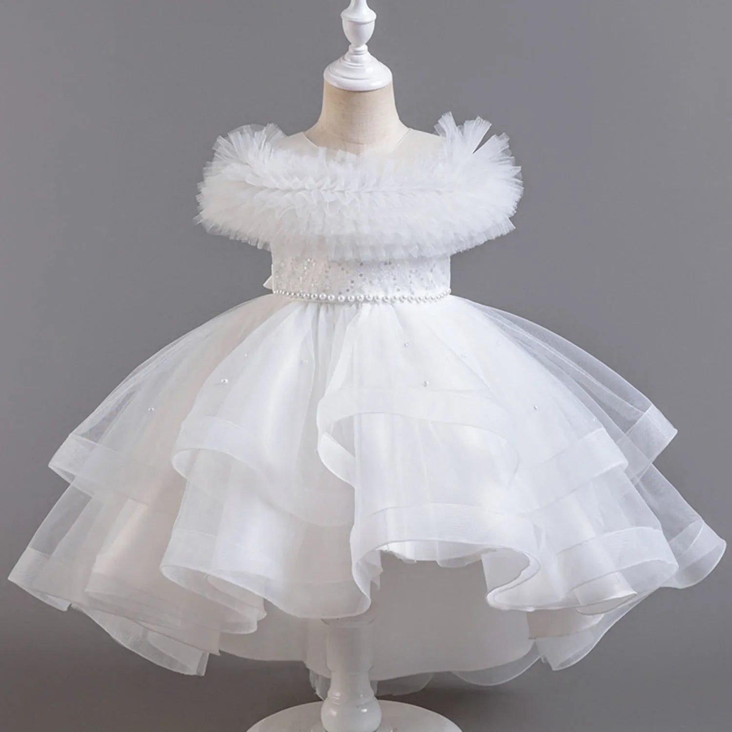 White children's dress on a mannequin against a gray background