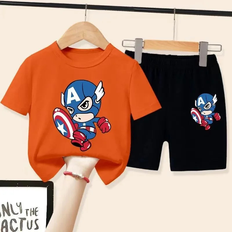 Orange t-shirt and black shorts with Captain America design on hangers against a beige background.
