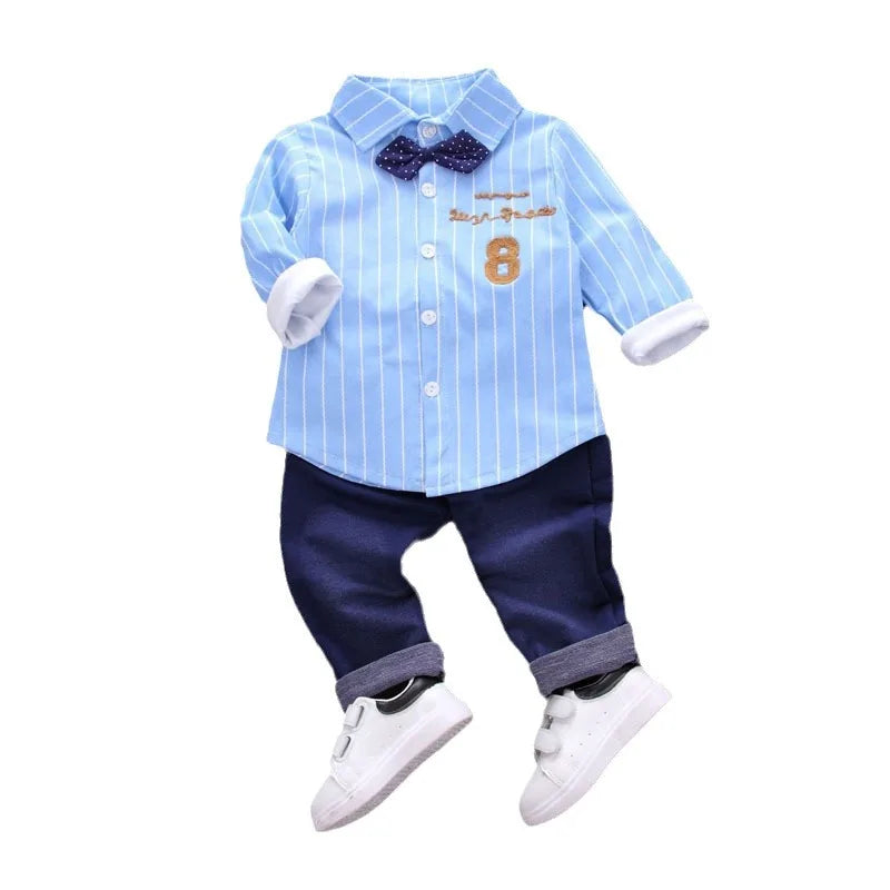 Children's outfit with blue striped shirt, navy pants, and white shoes on a white background